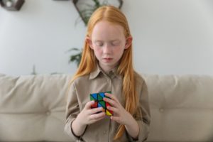 a child playing with a rubik's cube to help promote her speech therapy at home