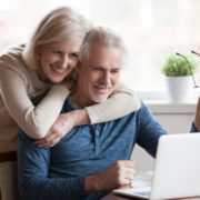 a man with Parkinson's at home on his laptop with his wife next to him