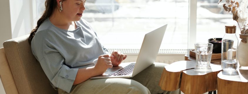 Teenage girl with special needs using her laptop next to a window