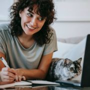 a woman with pen and paper researching lisp disorders while smiling
