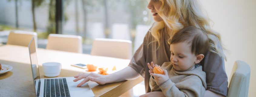 a young child learning from home on a laptop with a mother