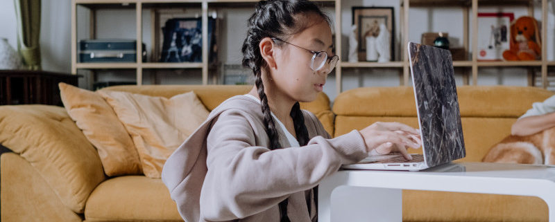 a girl with tongue thrust at home on her laptop getting online speech therapy