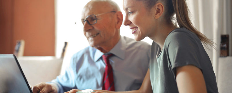 a woman helping her grandfather who suffers dementia on the computer at home