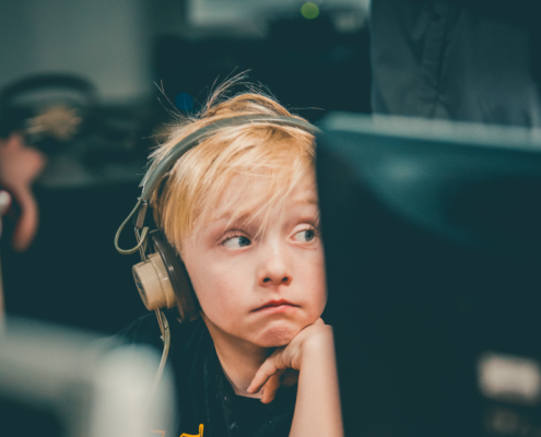 child with headphones on blocking out noise