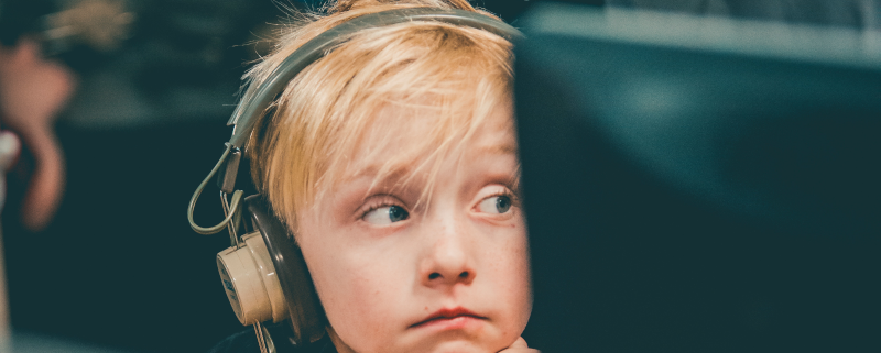 child with headphones on blocking out noise