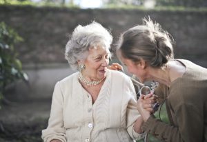 a woman helping an elderly woman with her communication skills outdoors