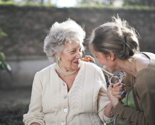 a woman helping an elderly woman with her communication skills outdoors