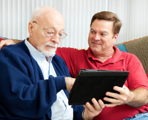 man teaching his father to use a tablet
