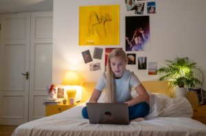 a teenage girls sitting on her bed with a laptop